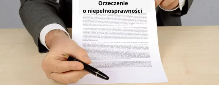 Obrazek wyróżniający do artykułu - orzeczenie o niepełnosprawności. Na zdjęciu widać mężczyznę w ciemnym garniturze, siedzącego za biurkiem i podpisującego dokument zatytułowany "Orzeczenie o niepełnosprawności". Mężczyzna trzyma w ręku czarny długopis, a dokument, który podpisuje, jest szczegółowo napisany i umieszczony na jasnym biurku. Scena ta podkreśla formalny charakter procedury, w której osoba wydaje się być odpowiedzialna za rozstrzygnięcia związane z orzeczeniem o niepełnosprawności. Na zdjęciu dominuje uczucie oficjalności i odpowiedzialności związanej z przetwarzaniem ważnych dokumentów prawnych.